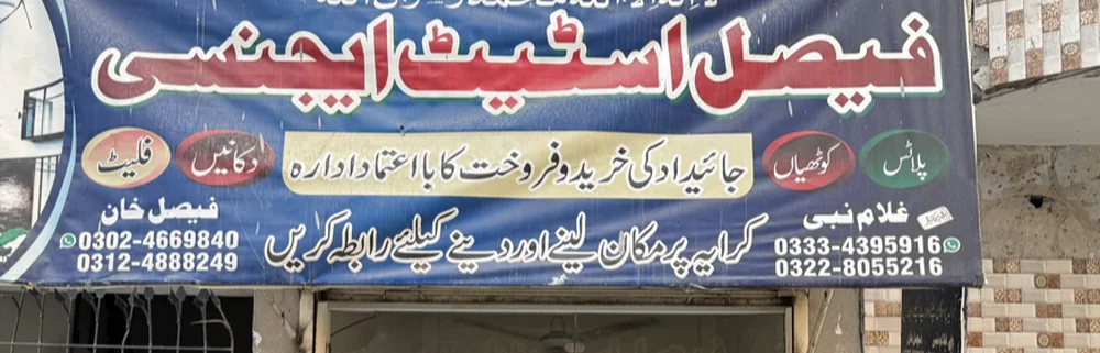 The real Faisal Estate Agency board on Multan Road: red Nastaliq name, cream ovals for plots, kothis, shops and flats